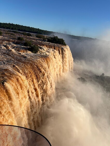 A waterfall cascading over a rocky cliff, surrounded by a forested landscape. 1