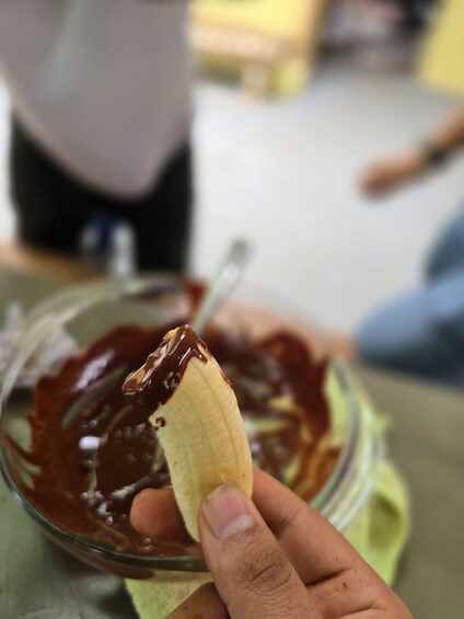 A hand holding a banana with chocolate spread. 3