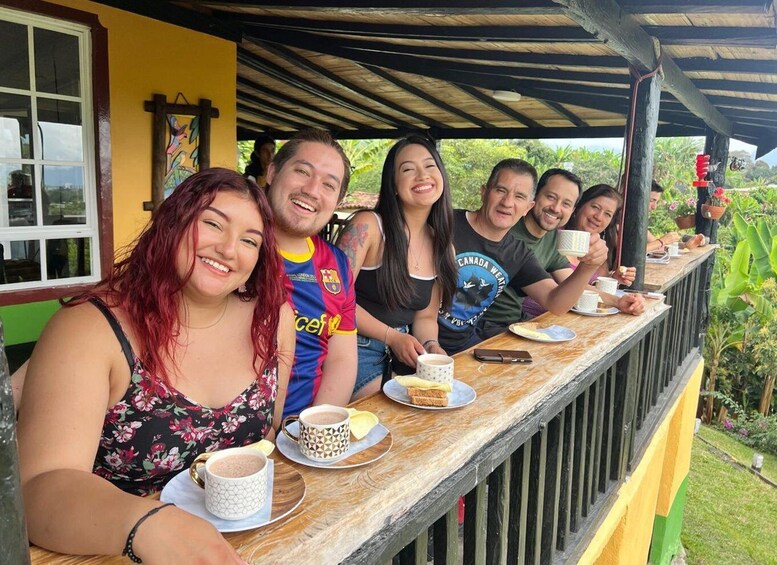 A group of people sitting at an outdoor café with coffee cups and sandwiches. 1