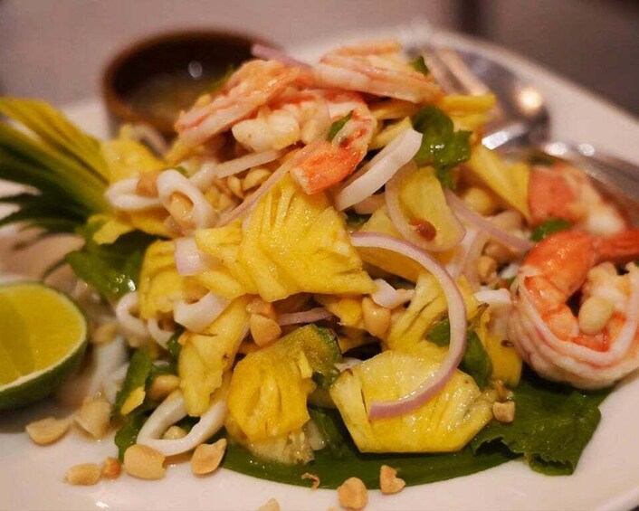 A plate of shrimp and pineapple salad with a lime wedge. 3