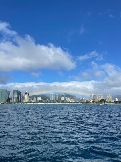 A city skyline with a rainbow over the water. 1