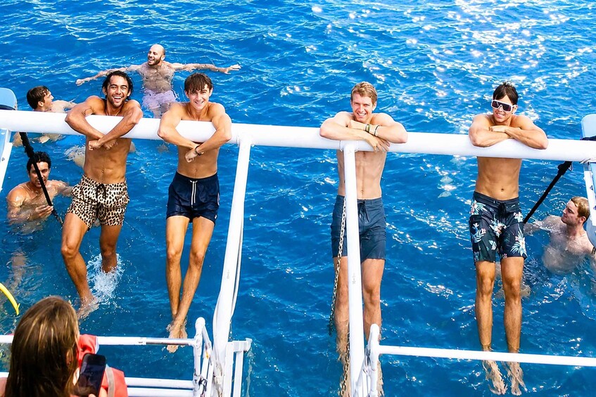 People in a swimming pool with some standing on a boat's railing. 2