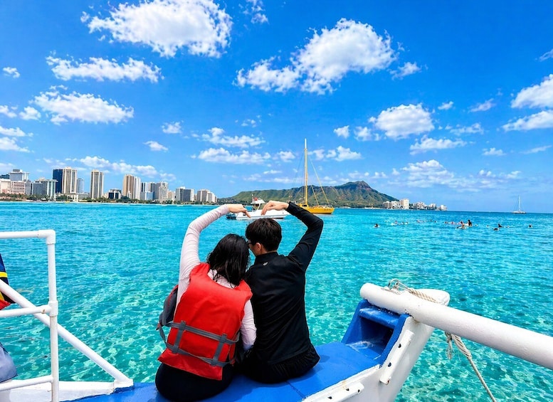 A couple on a boat with a city skyline and mountains in the background. 3