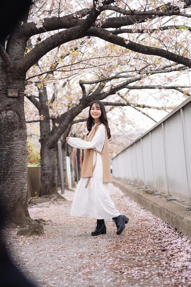 A person walking along a tree-lined path with cherry blossoms. 2