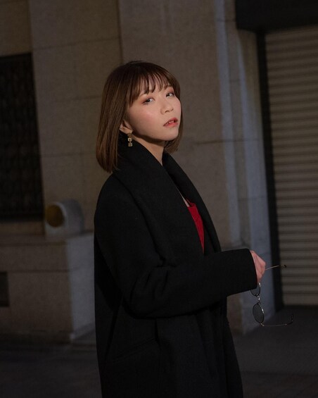 A person standing in front of a building with a closed shutter. 4