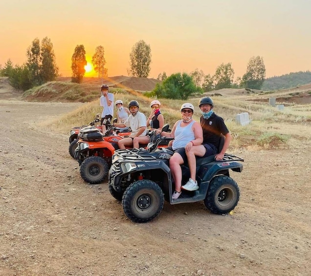 A group of people on ATVs on a dirt road with a sunset in the background. 3