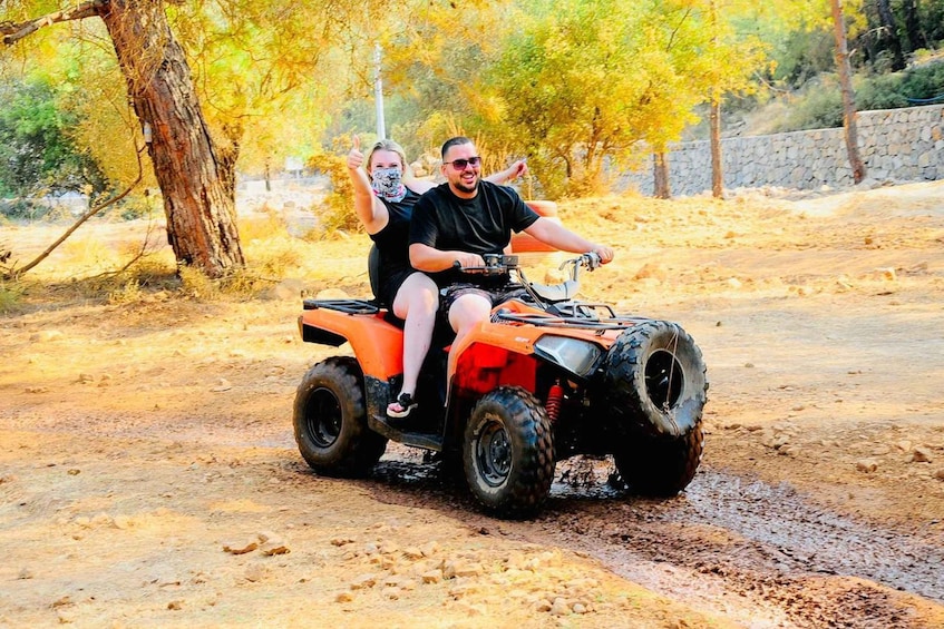 A person riding an ATV on a dirt path surrounded by trees. 4