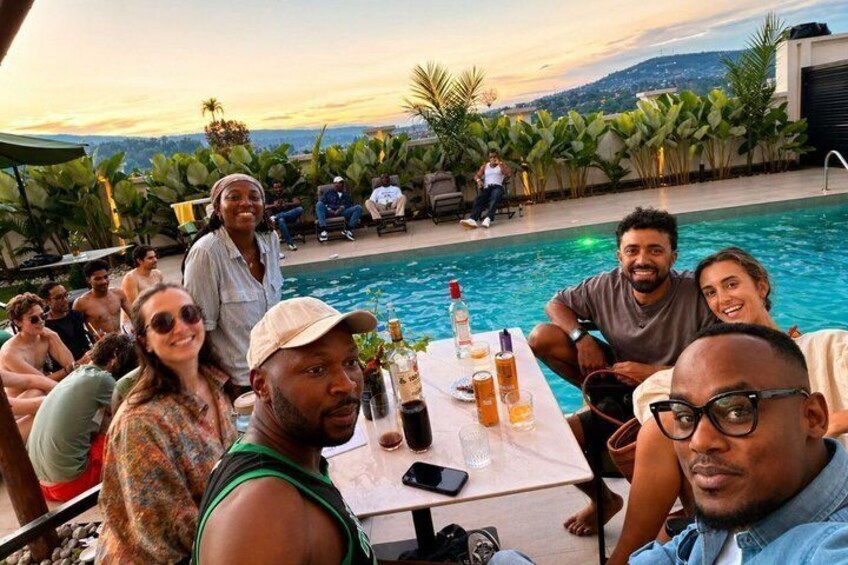 A group of people around a pool with a sunset in the background. 4