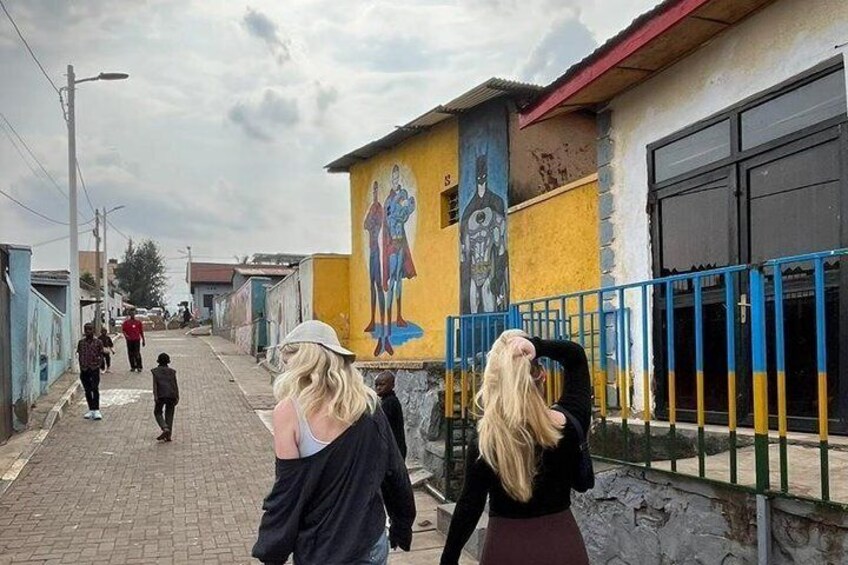 A street with pedestrians, a mural, and a blue fence. 3