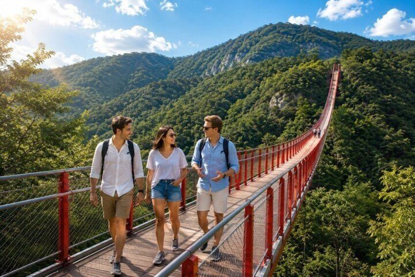 A suspension bridge with red railings, surrounded by lush green mountains and trees. 3