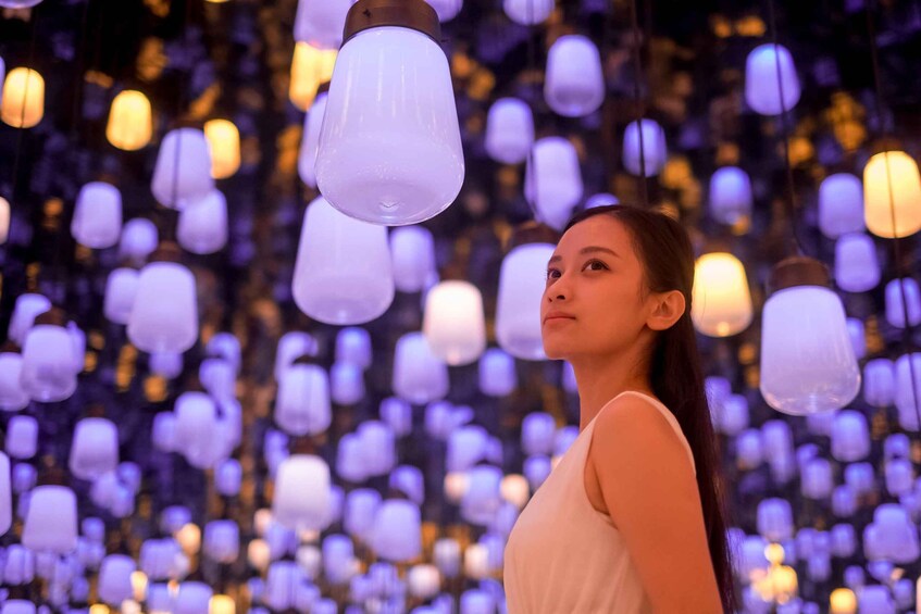 A person standing in front of a backdrop of hanging light bulbs. 1