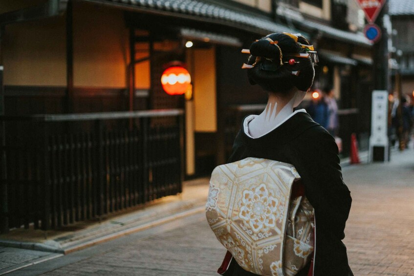 A person in traditional attire walking on a street with a patterned bag. 2