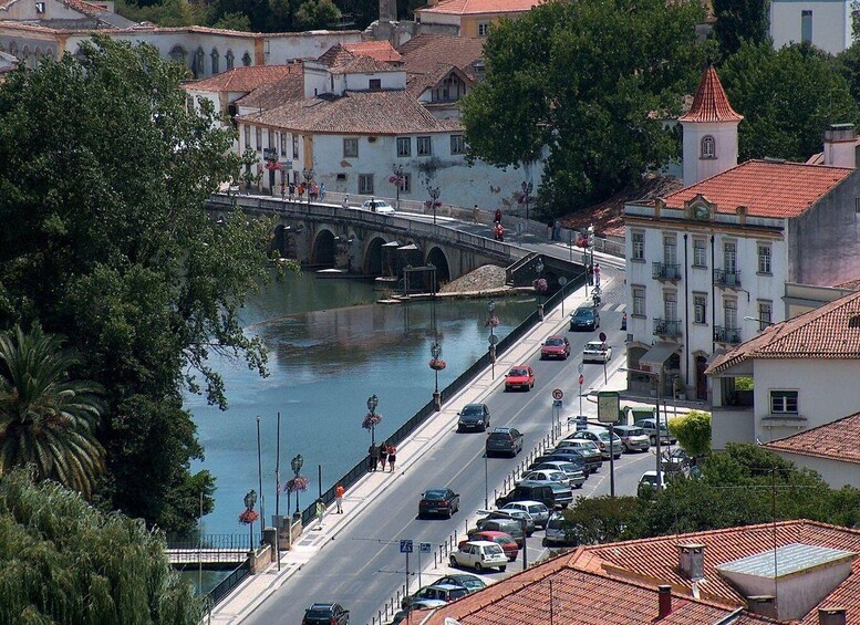 A river with a bridge, cars on the road, and buildings with red roofs. 1