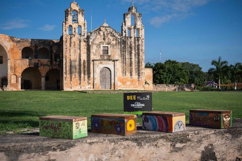 A historic church with a sign for 'BEE Matters' and colorful painted blocks in front. 3