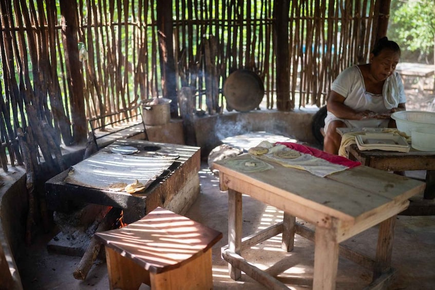 An outdoor cooking area with a charcoal stove, cooking utensils, and a person preparing food. 5