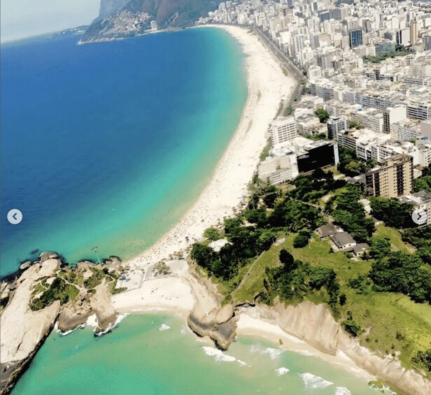 A coastal city with a long sandy beach, clear blue waters, and dense urban buildings. 2