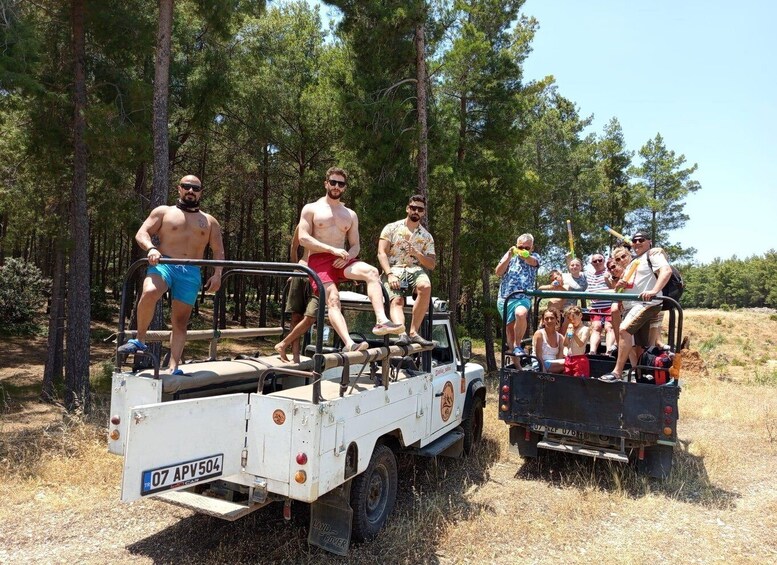 A group of people on a white Land Rover and a black Land Rover in a forested area. 3