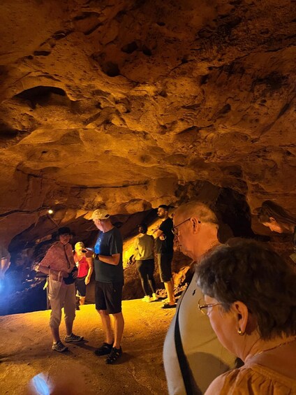 People exploring a cave with rocky walls and a warm light source. 2
