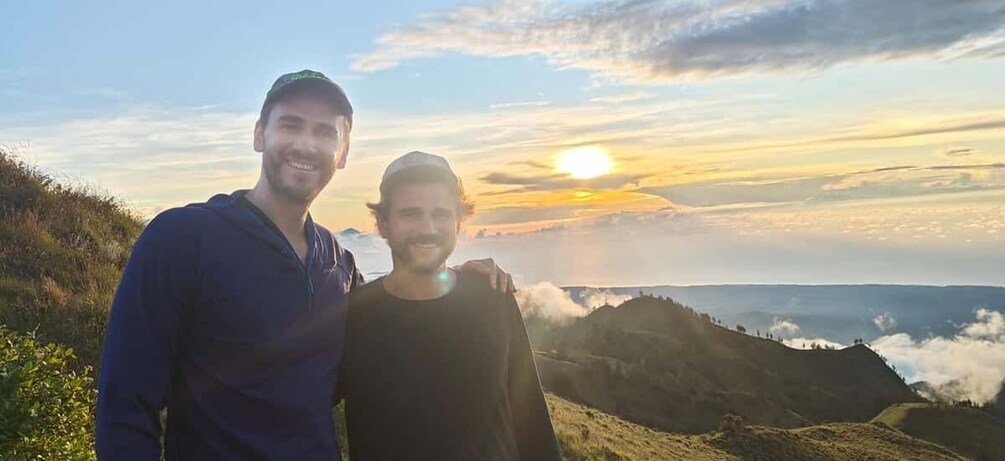Two people standing on a hill with a sunset in the background. 3