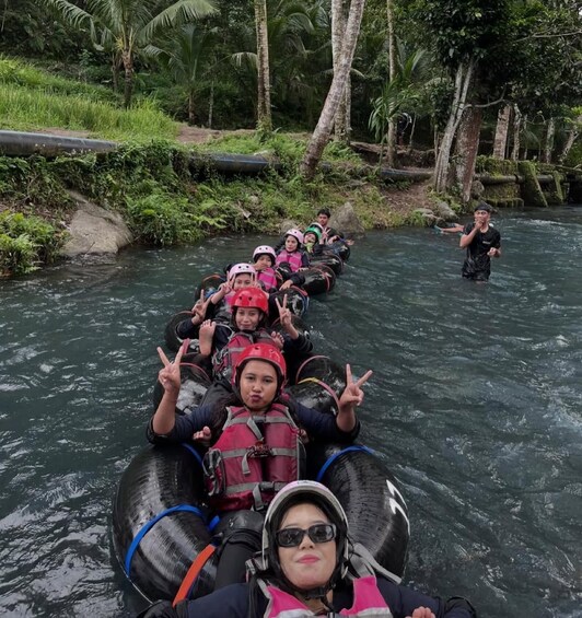 A group of people rafting down a river surrounded by greenery. 5