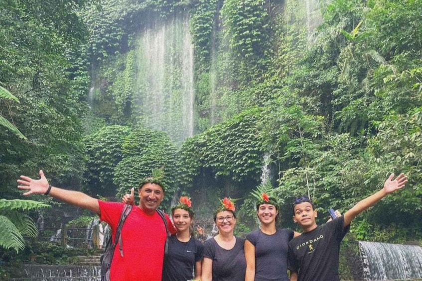 Un grupo de personas frente a una cascada rodeada de exuberante vegetación. 2
