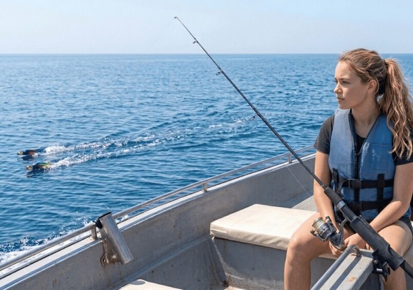 A person fishing on a boat with the ocean in the background. 4