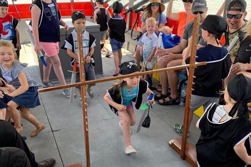 A group of people, including children and adults, gathered around a wooden structure, possibly a playground or obstacle course. 5