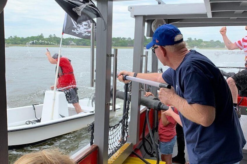 A boat with a pirate flag, a person in a red life jacket, and another person in a blue shirt. 2