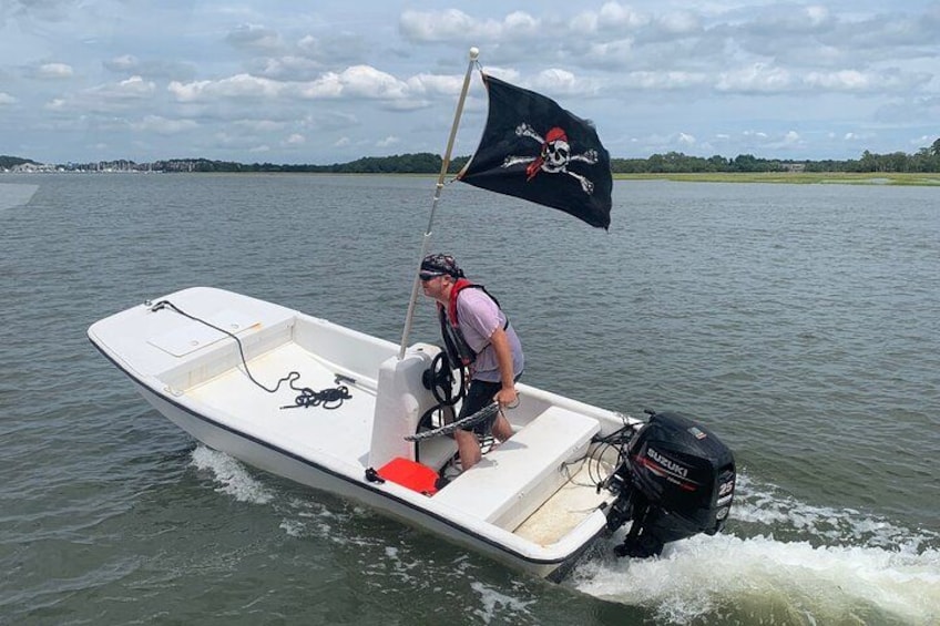 A person on a small motorboat with a flag, on a body of water. 5