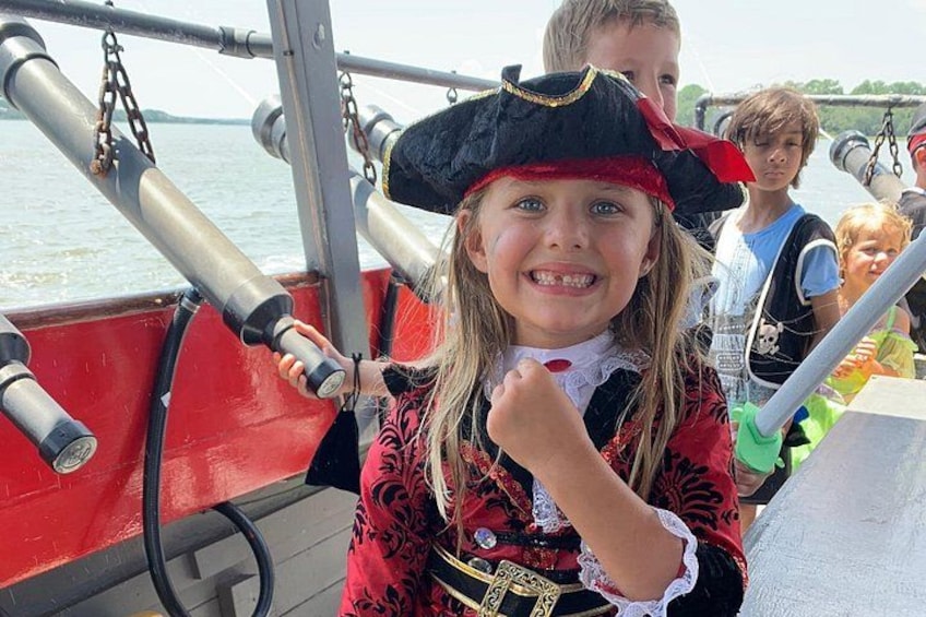 A person in a pirate costume on a boat with cannons. 3