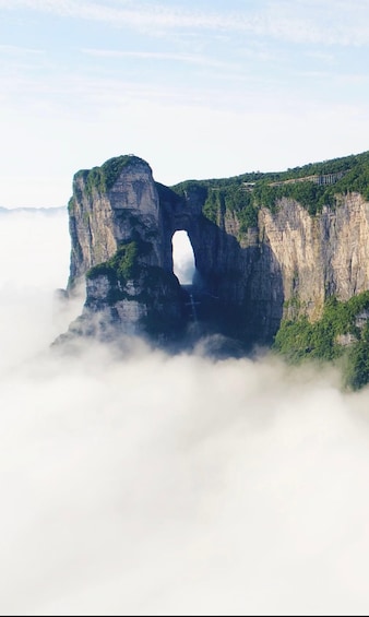 A natural rock arch formation surrounded by clouds. 1