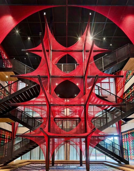 A modern architectural structure with red netting and black staircases. 2