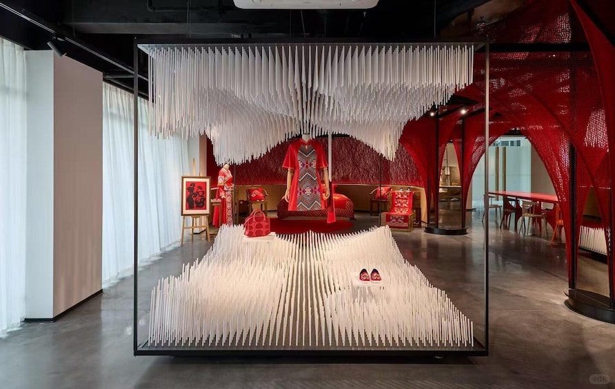 A modern interior with a central display of vertical white structures, red furniture, and a red patterned wall. 4