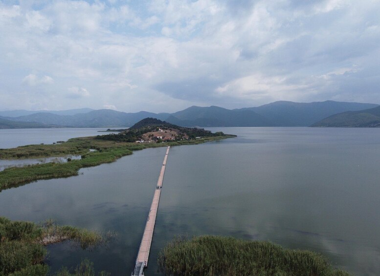 Un largo puente sobre un lago tranquilo con montañas al fondo. 1
