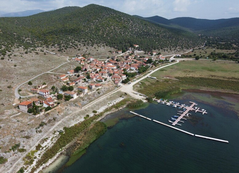 Un pueblo costero con casas de techo rojo, un puerto deportivo y colinas circundantes. 3