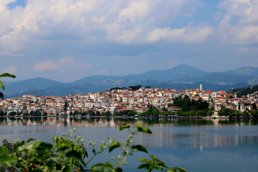 Un paisaje urbano costero con un denso conjunto de edificios, una torre destacada y un lago tranquilo que refleja las estructuras. 2