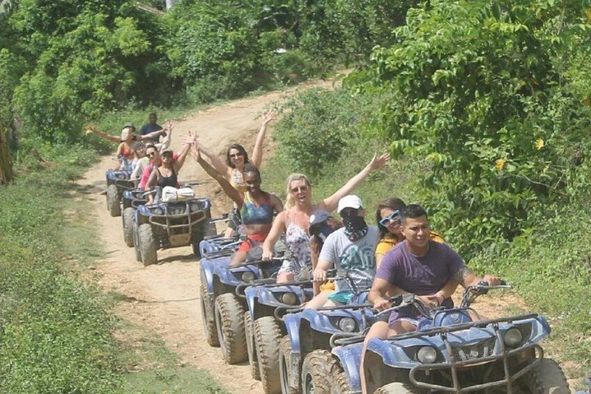 People riding ATVs on a dirt path surrounded by greenery. 1