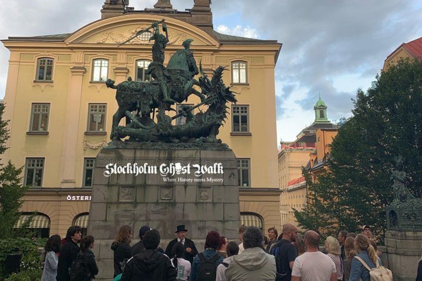 Una statua raffigura una scena di battaglia di fronte a un edificio con il cartello 'Stockholm Ghost Walk'. 3