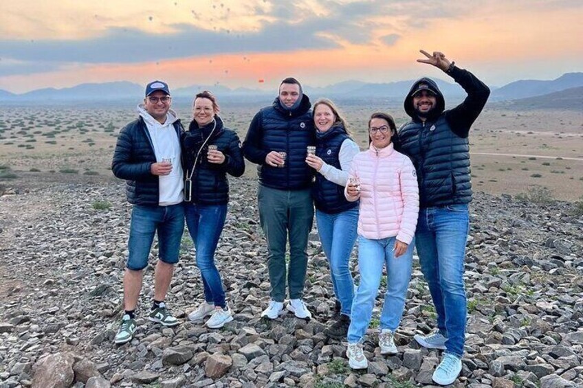 A group of people standing on rocky terrain with a sunset in the background. 5