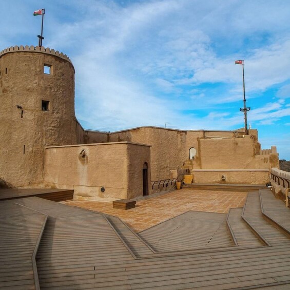 A historic fort with a round tower, a flagpole, and a paved courtyard. 4