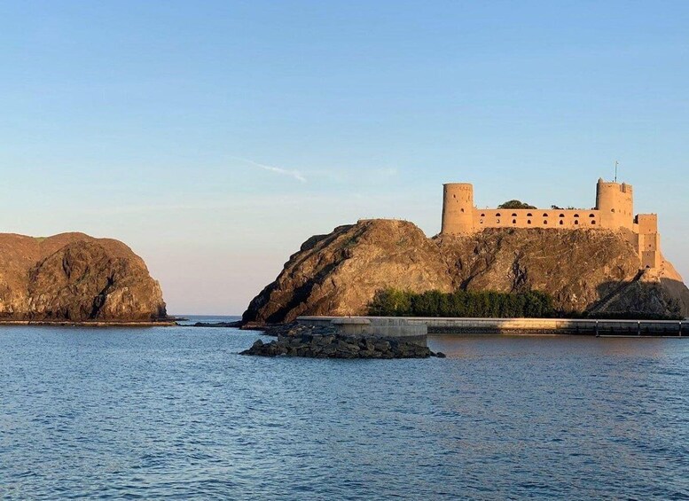 A coastal castle on a rocky outcrop with a clear sky. 1