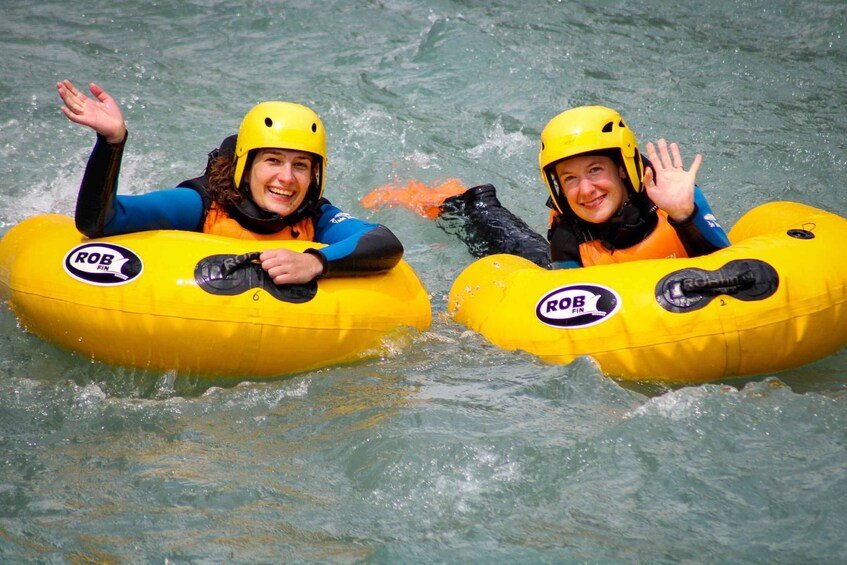 Two people in yellow inflatable rafts with helmets, labeled 'ROB FIN,' on a body of water. 1