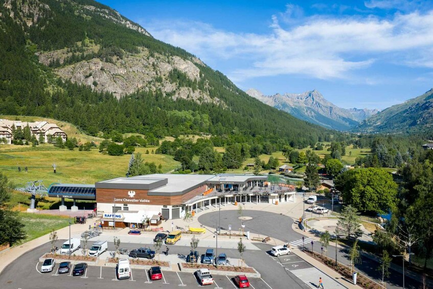 A parking lot with cars, a building labeled 'Sarre Chevalier Vallee,' and a mountainous landscape in the background. 5