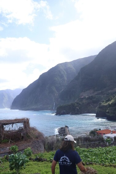 A person standing on a grassy area overlooking a coastal landscape with cliffs and a body of water. 2