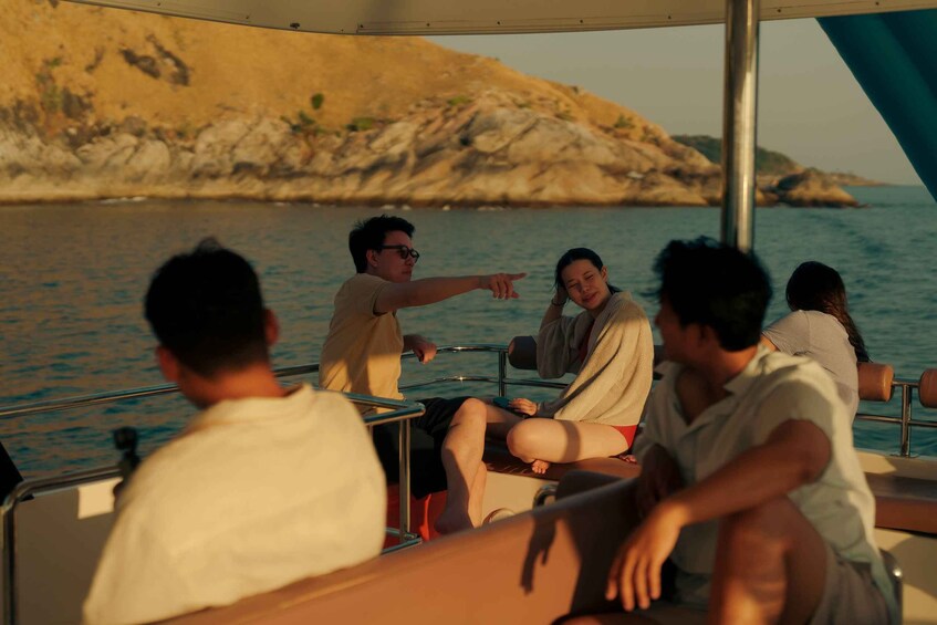 A group of people on a boat with a rocky coastline in the background. 1