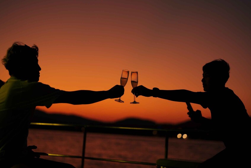 Two people toasting with champagne glasses against a sunset. 3