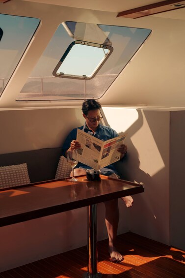 A person reading a newspaper in a room with a skylight. 4