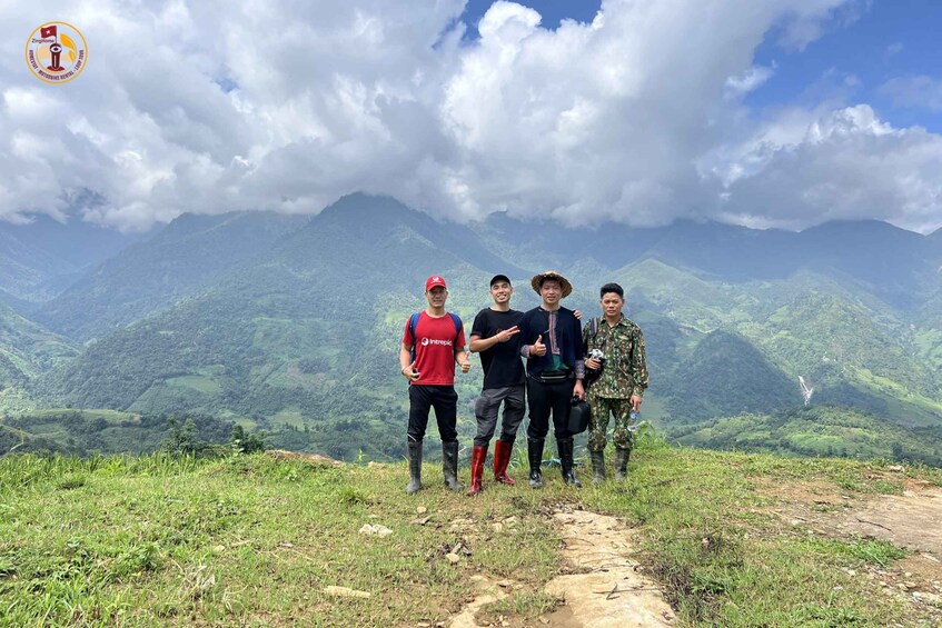 Four people standing on a mountain path with a mountainous landscape in the background. 5