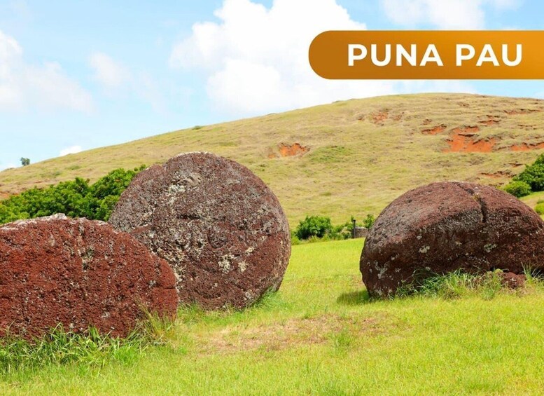 Three large boulders in a grassy field with a hill in the background. 2