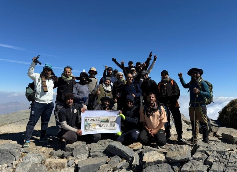 A group of hikers on a mountain with a banner reading 'RAWNAQ TRAVEL'. 1